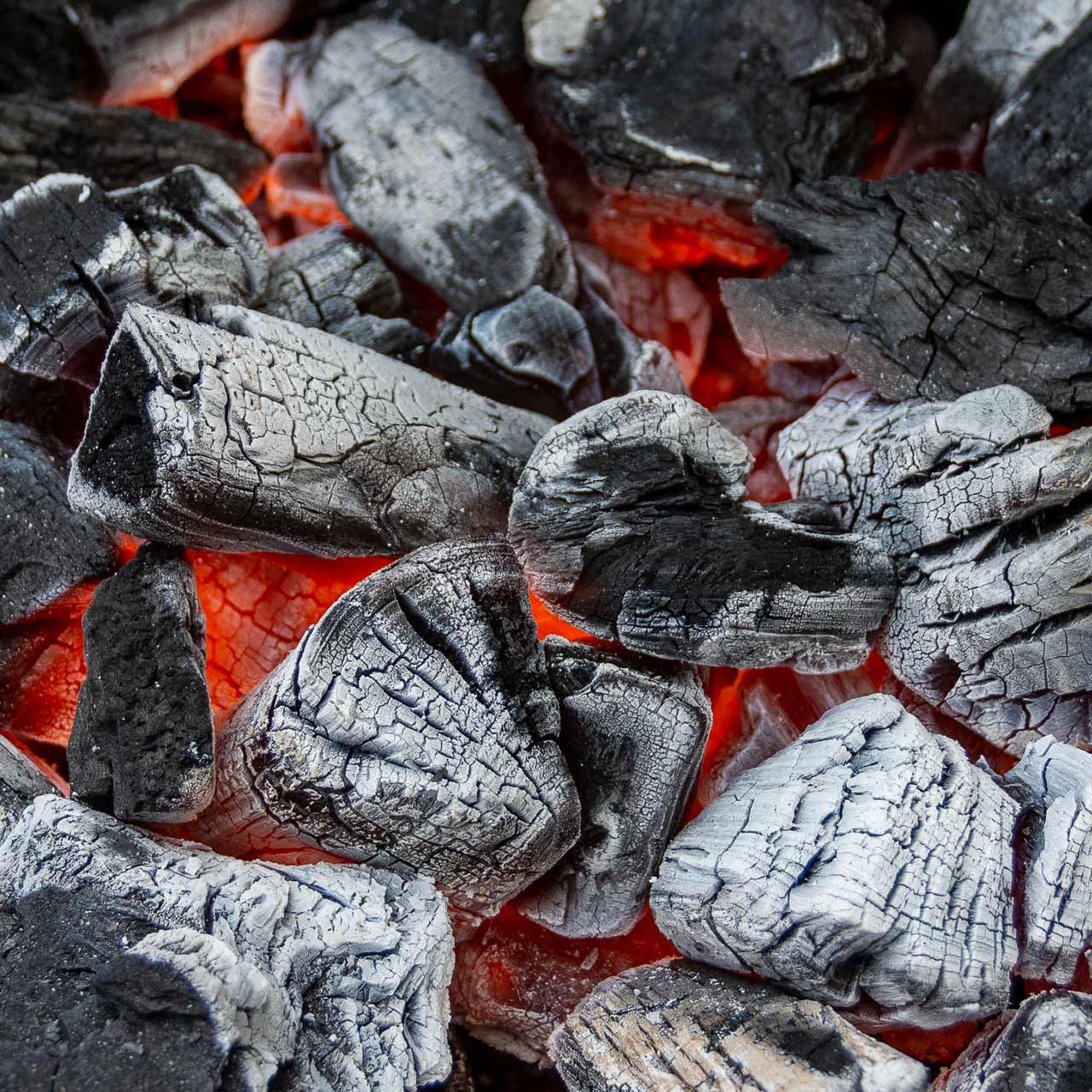Close-up of charcoal briquettes with glowing embers